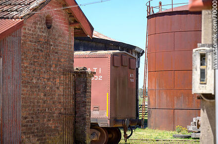 Parte posterior de un vagón de AFE entre construcciones y tanque - Departamento de Florida - URUGUAY. Foto No. 70000