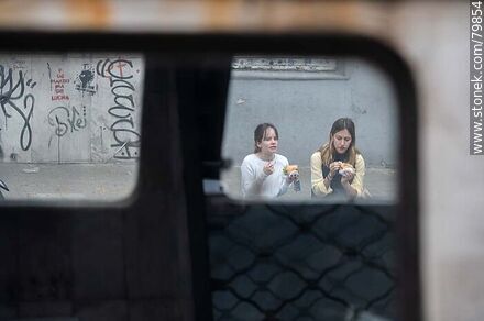 Niñas comiendo vistas a través del vidrio de un auto - Departamento de Montevideo - URUGUAY. Foto No. 79854