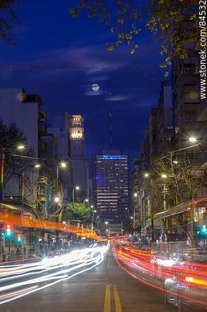 18 de Julio Avenue. Gaucho Tower. Trail of lights left by the traffic at dusk. The full moon - Department of Montevideo - URUGUAY. Photo #84532